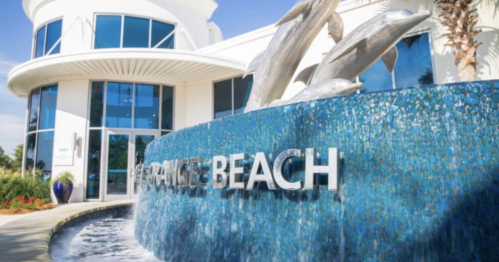 A modern building with a water feature and dolphins, featuring the words "Dance Beach" prominently displayed.