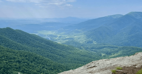 A panoramic view of lush green mountains and valleys under a clear blue sky.