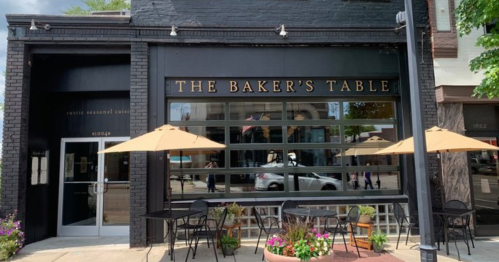 Exterior of The Baker's Table restaurant, featuring large windows, outdoor seating, and a welcoming entrance.