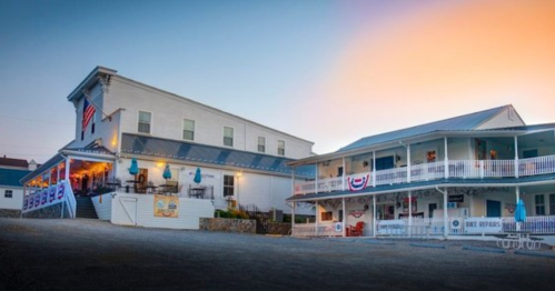 Historic buildings with porches and American flags, set against a colorful sunset sky.