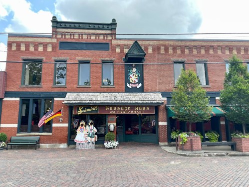 Exterior of a brick restaurant named "Sausage Haus," featuring decorative elements and a welcoming entrance.