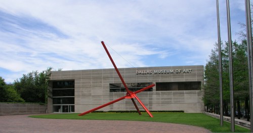 Exterior of the Dallas Museum of Art featuring a large red sculpture in front and a modern building design.