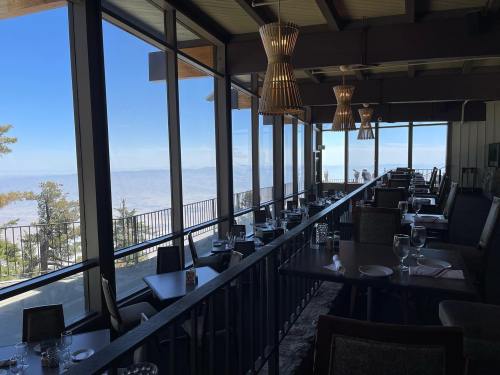 A modern restaurant interior with large windows offering a scenic view, featuring tables set for dining.