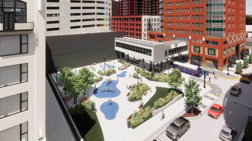 Aerial view of a modern urban park with water features, surrounded by buildings and parked cars.