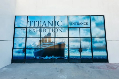 Entrance to "Titanic: The Exhibition" featuring a large image of the Titanic against a cloudy sky.