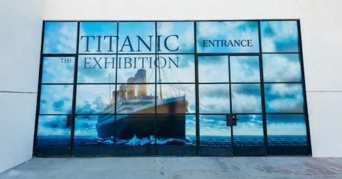 Entrance to "Titanic: The Exhibition" featuring a large image of the Titanic against a cloudy sky.