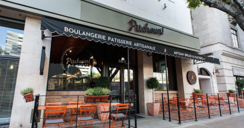 Exterior of Pitchoun! bakery with outdoor seating and a striped awning, showcasing a welcoming atmosphere.
