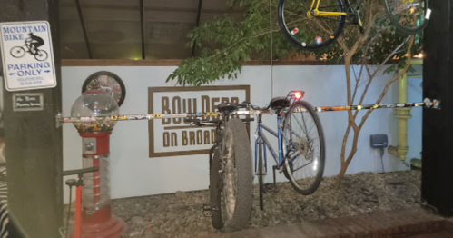 A bike hanging on a rack next to a gumball machine in a cozy outdoor setting.