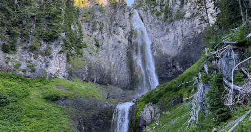A scenic waterfall cascading down rocky cliffs, surrounded by lush greenery and trees.