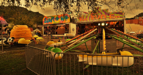 A colorful carnival scene featuring rides, games, and playful decorations under a cloudy sky.