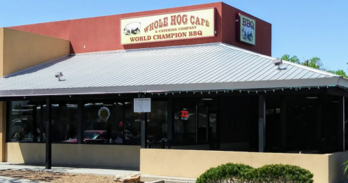 Exterior of Whole Hog Cafe, featuring a sign that reads "World Champion BBQ" and a modern building design.