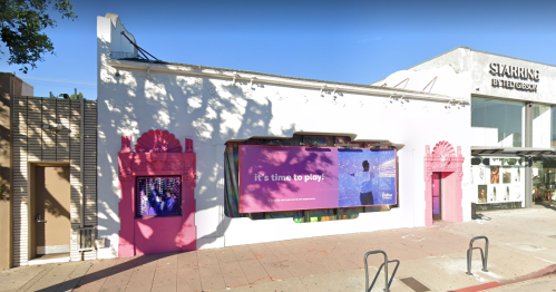 A colorful building exterior with a large pink banner that reads "it's time to play" and decorative architectural features.