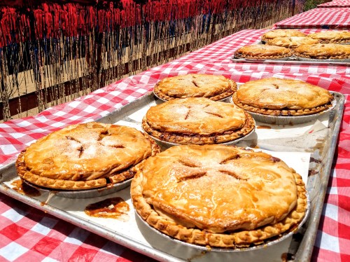 Freshly baked pies on a checkered tablecloth, with a colorful backdrop of red and blue decorations.