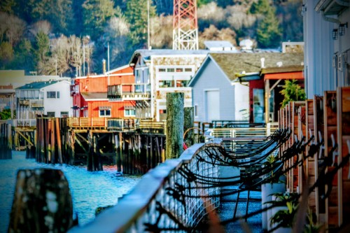 Colorful buildings line a waterfront, with wooden docks and a calm waterway reflecting the scenery.