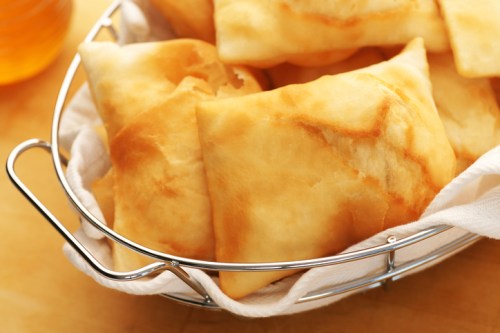A basket of golden, flaky pastries resting on a white cloth.