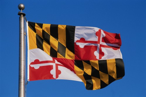 Maryland state flag featuring black and gold stripes and red and white crosses against a blue sky.
