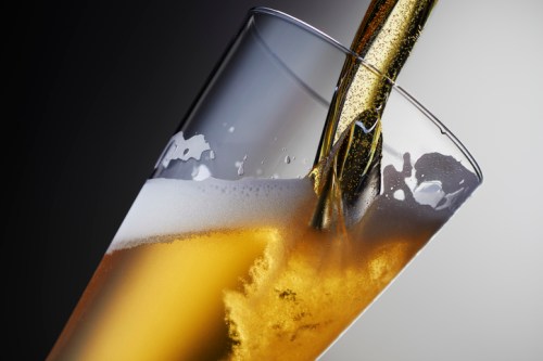 A close-up of a glass being filled with golden beer, creating bubbles and foam.