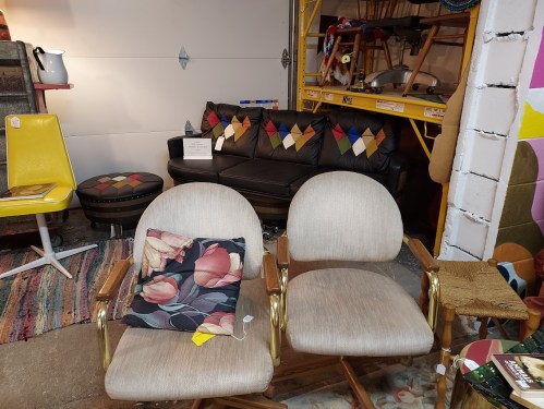 A cozy vintage seating area featuring two armchairs, a patterned couch, and decorative pillows in a colorful space.