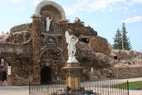 A unique stone structure with intricate designs, featuring a statue of an angel and a religious figure at the entrance.