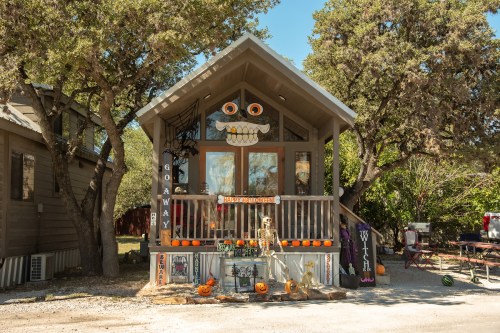 A decorated house with Halloween themes, featuring pumpkins, skeletons, and spooky decorations on the porch.