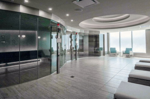 Modern spa interior featuring glass walls, lounge chairs, and soft lighting, creating a serene atmosphere.