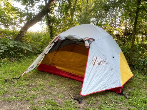 A colorful tent set up in a grassy area surrounded by trees.