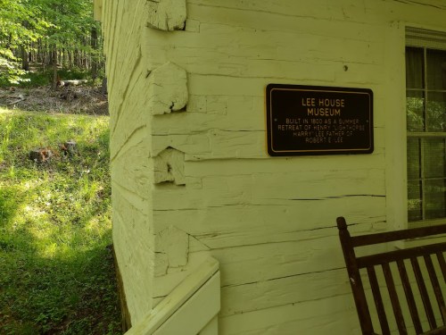 Sign on a white wooden building reading "Lee House Museum," surrounded by greenery.