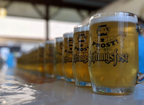 A row of beer mugs with "Prost!" and "Stiftungsfest" printed on them, set on a table.
