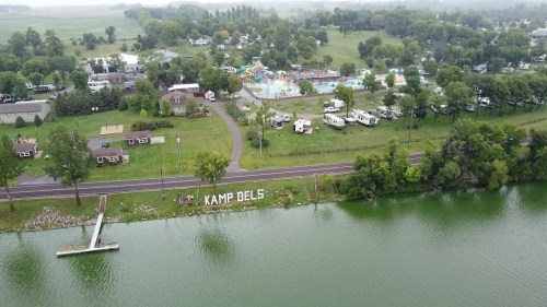 Aerial view of Kamp Dels, featuring a lake, RVs, and a water park in a green landscape.