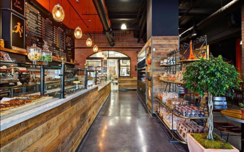 A modern café interior featuring a wooden counter, display cases, and decorative lighting in a cozy atmosphere.
