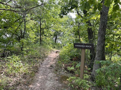 A dirt path leads through lush greenery, with a signpost reading "Hanging Rock" visible among the trees.