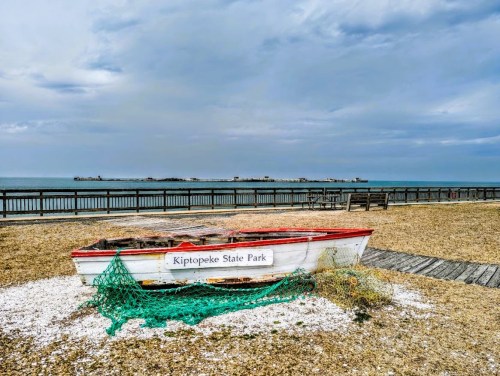 A weathered boat at Kiptopeke State Park, with a cloudy sky and calm waters in the background.