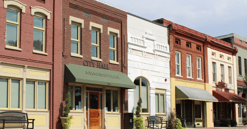 Historic buildings line a street, featuring City Hall and colorful storefronts in Adairsville.