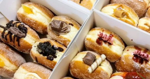 A box of assorted filled donuts topped with various sweet toppings and glazes.