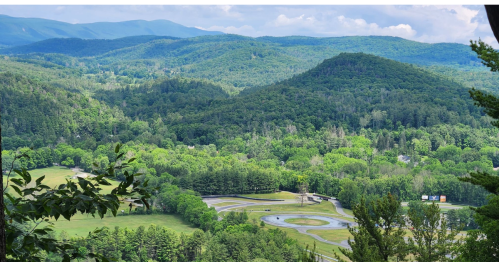 A panoramic view of lush green mountains and valleys under a partly cloudy sky.