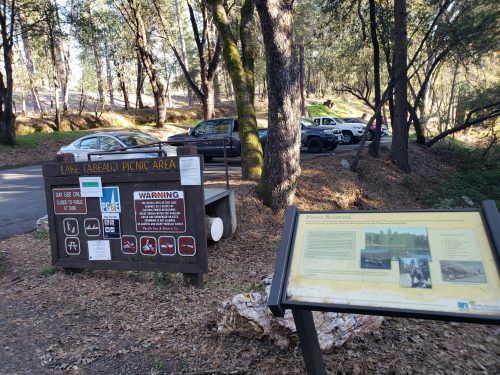Signage for Lake Tabegand picnic area with parked cars and trees in the background.