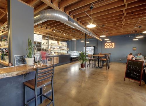 A modern café interior with wooden beams, a bar area, seating, and an "OPEN" sign on a chalkboard.