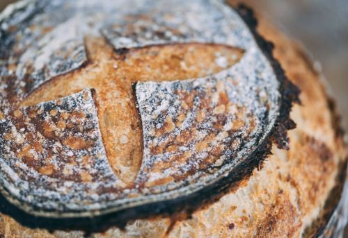 Close-up of a freshly baked round loaf of bread with a cross pattern on top and a golden-brown crust.