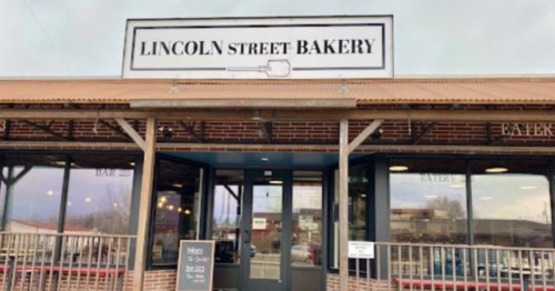 Exterior of Lincoln Street Bakery, featuring a sign and large windows, with a welcoming entrance and outdoor seating.