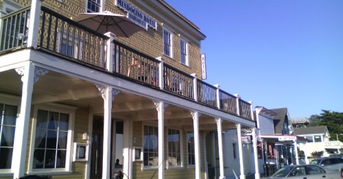 Historic building with a balcony, sign reading "Mendocino Hotel," and clear blue sky in the background.