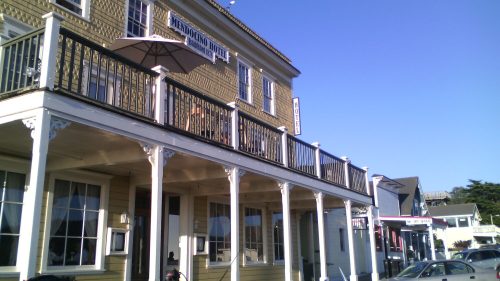Historic building with a balcony, sign reading "Mendocino Hotel," and clear blue sky above.