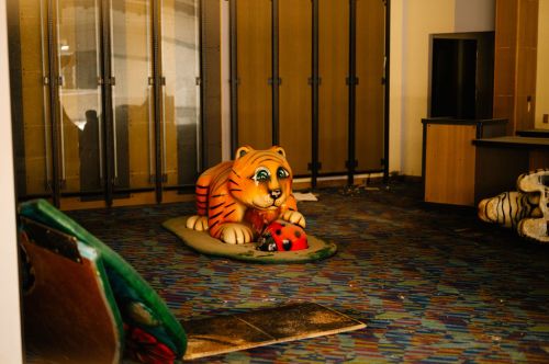 An abandoned room featuring a large, colorful tiger statue and scattered debris on the floor.