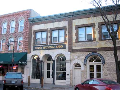 Historic building of First National Bank with large windows, located in a quaint downtown area.