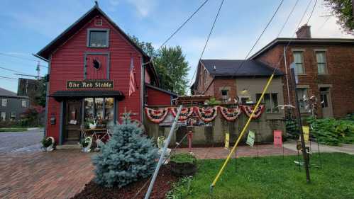 A red building with "The Red Stable" sign, decorated with bunting, surrounded by greenery and power lines.