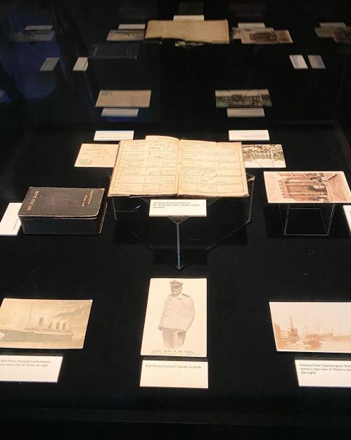 A display case featuring historical documents, photographs, and a ledger, showcasing maritime history artifacts.