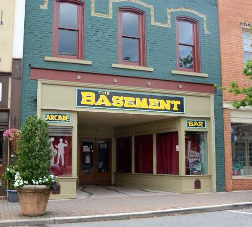 A storefront labeled "The Basement" featuring an arcade and bar, with large windows and a colorful facade.