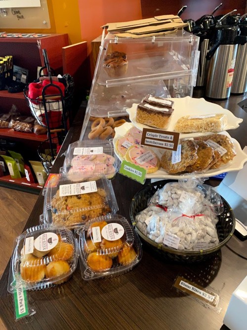 A display of assorted baked goods, including muffins, cookies, and pastries, in a café setting.