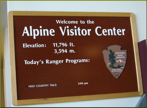 Sign for the Alpine Visitor Center, displaying elevation, ranger programs, and National Park Service logo.