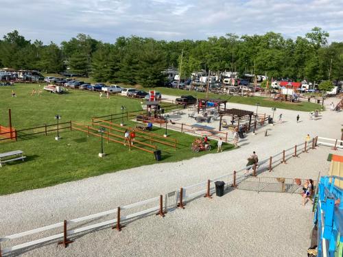 Aerial view of a campground with playground, picnic areas, and parked vehicles surrounded by trees.