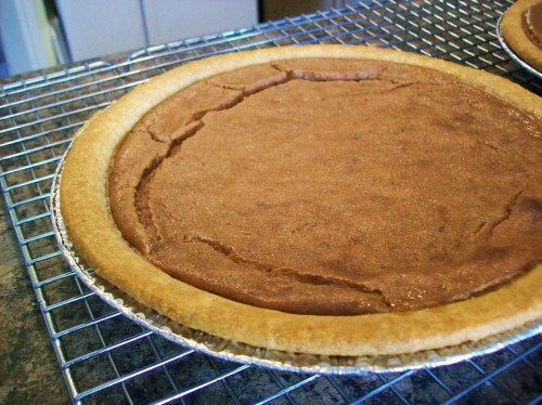 A freshly baked chocolate pie cooling on a wire rack, featuring a golden crust and a smooth, cracked filling.